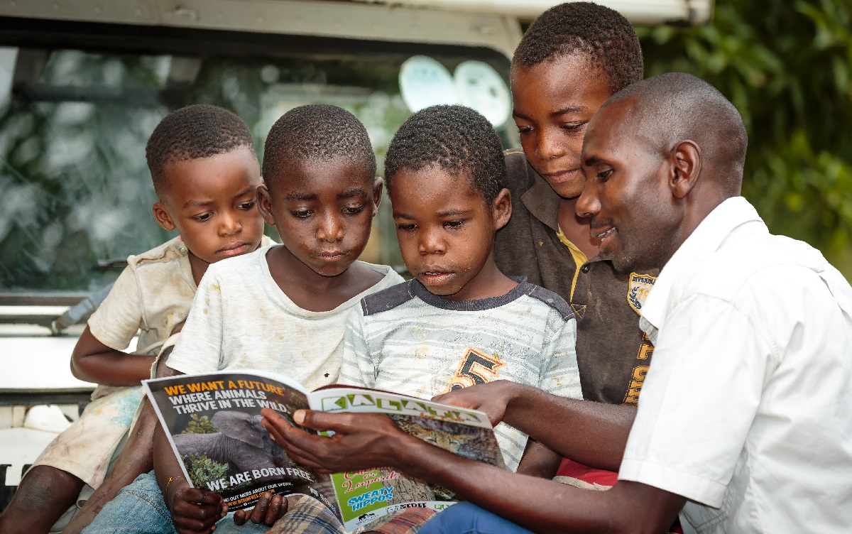 Children intently reading a wildlife magazine, supported by an Education Officer.