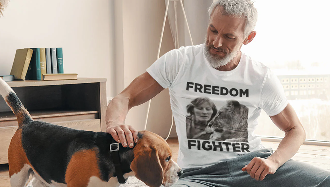 A grey-haired man wearing a Freedom Fighter T-shirt, petting a beagle