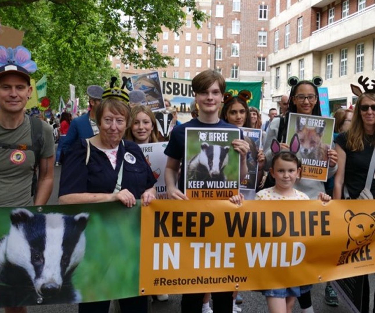 A crowd of people at a demonstration holding banners with images of wildlife on them