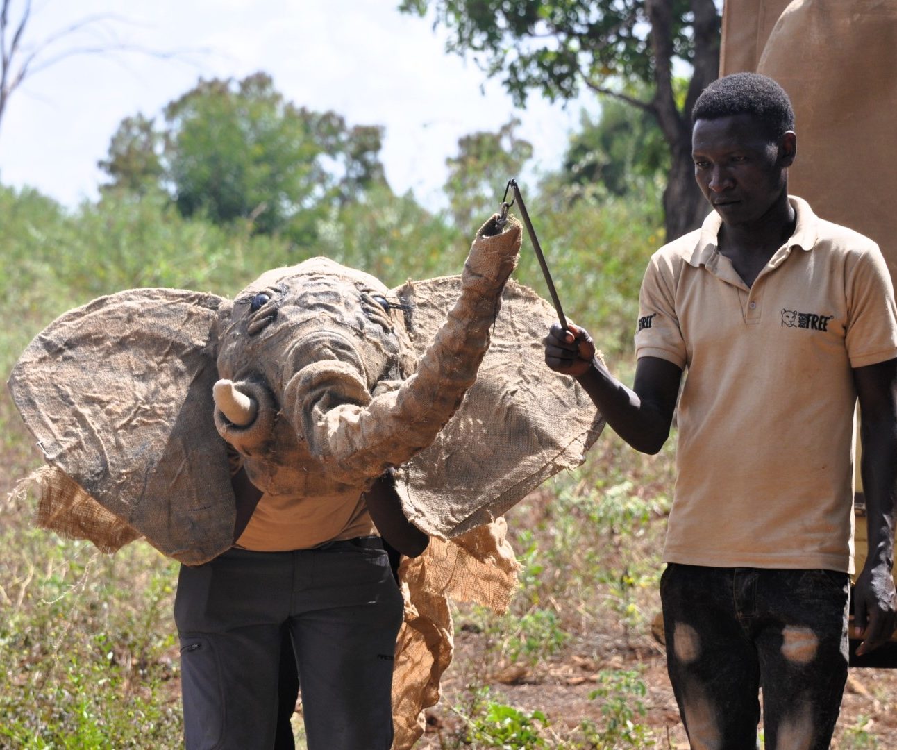 A man wearing a born free T-shirt controlling the trunk of an elephant puppet as part of a workshop in Kenya