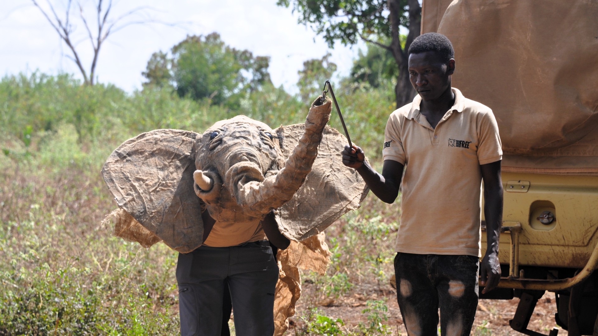 A man wearing a born free T-shirt controlling the trunk of an elephant puppet as part of a workshop in Kenya