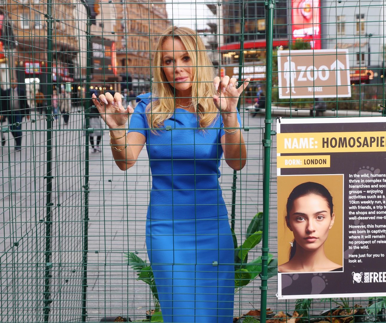 A woman wearing a blue dress standing in a cage in Leicester Square