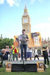 Dr Mark Jones stood on a platform in front of Big Ben and a large banner reading 'End The Cull'