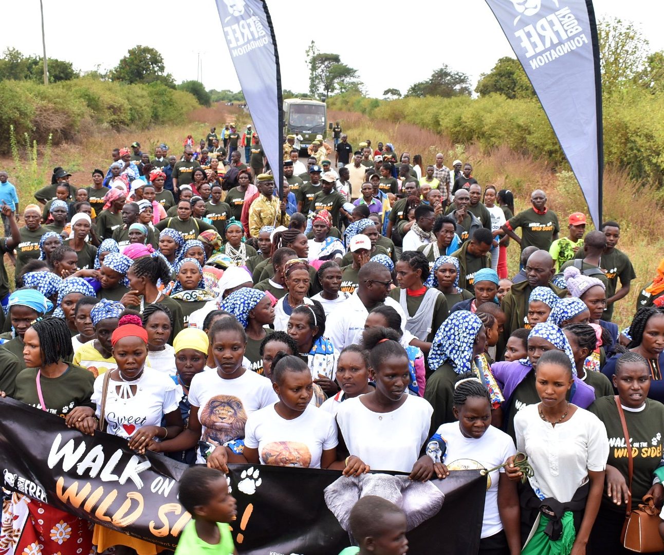 Hundreds of people wearing walk on the wild side T-shirts and holding Born Free banners, gather for the walk in Kenya