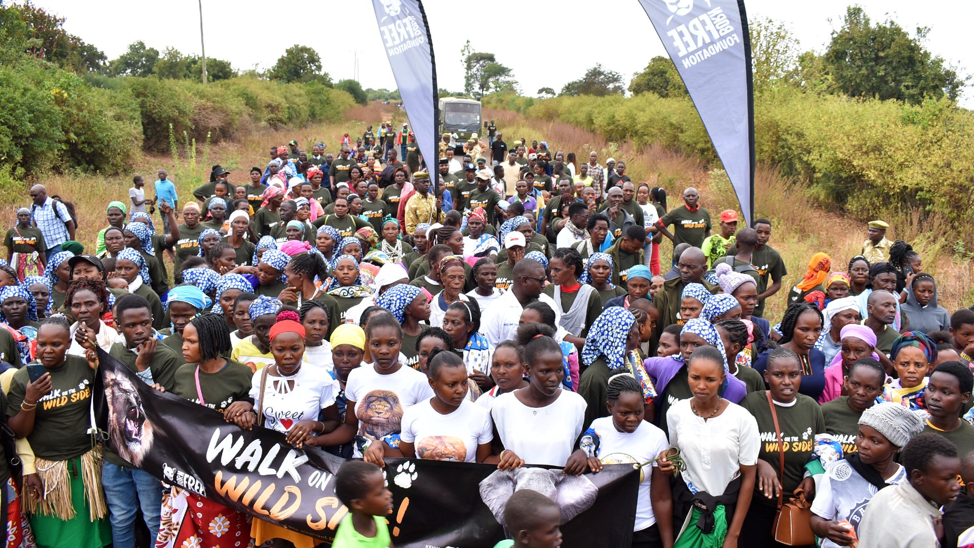 Hundreds of people wearing walk on the wild side T-shirts and holding Born Free banners, gather for the walk in Kenya