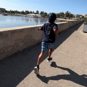 A young boy running alongside a river