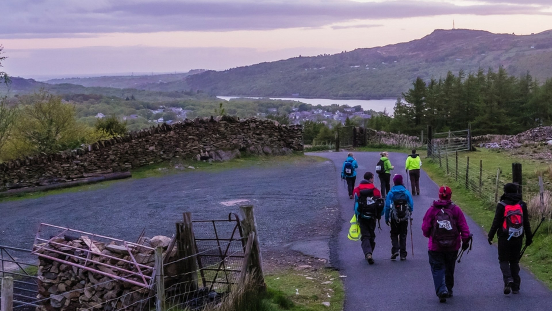 A group of people trekking up mount Snowdon at dusk