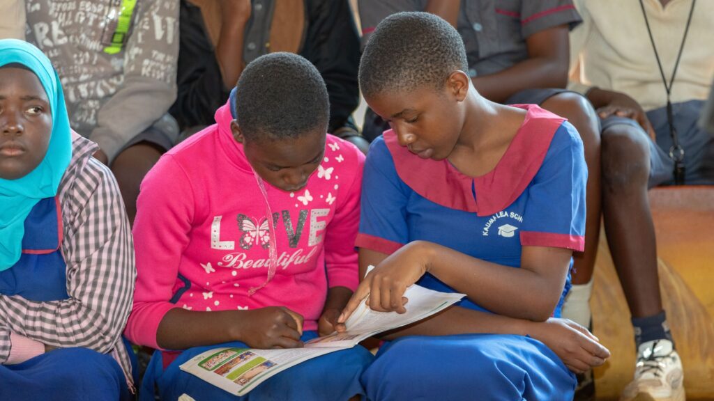 Two Malawian school children looking at an educational resource leaflet